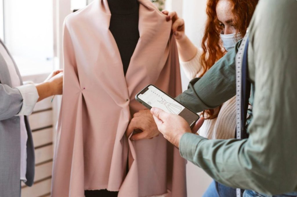 Group of fashion designers working in atelier and checking garment