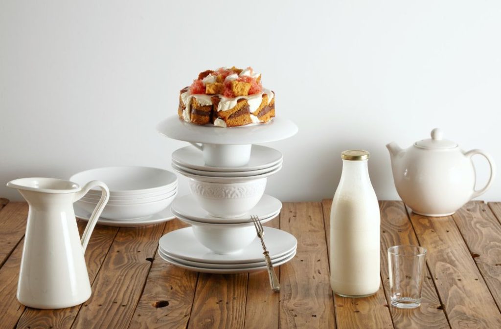 Delicate white tea set, milk bottle and mouthwatering sponge cake